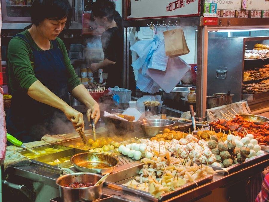 A busy night market with food stalls lit up after dark