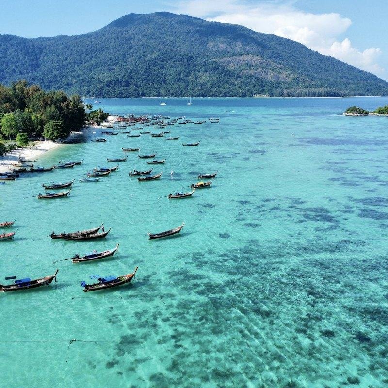 Longtail boats floating in clear water off a beach