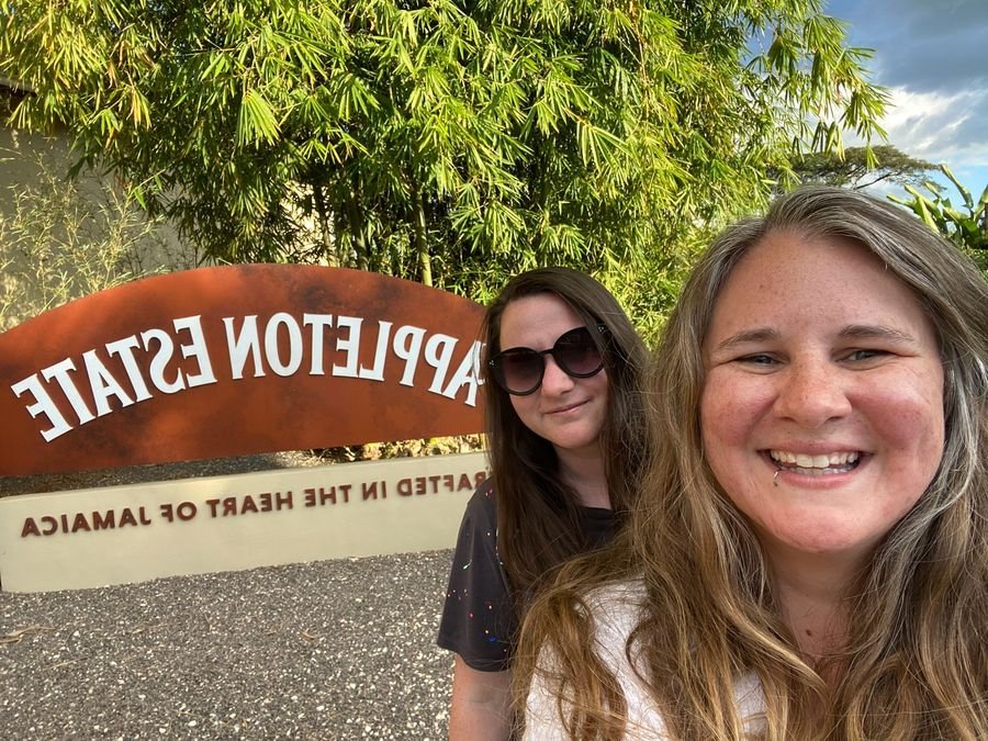 Mariya and Sam taking a selfie in front of the Appleton Estate sign in Jamaica