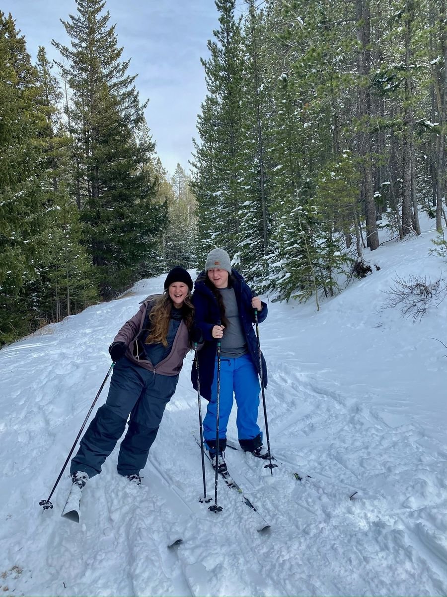 Mariya and Sam laughing on cross-country skis on a snowy forest trail