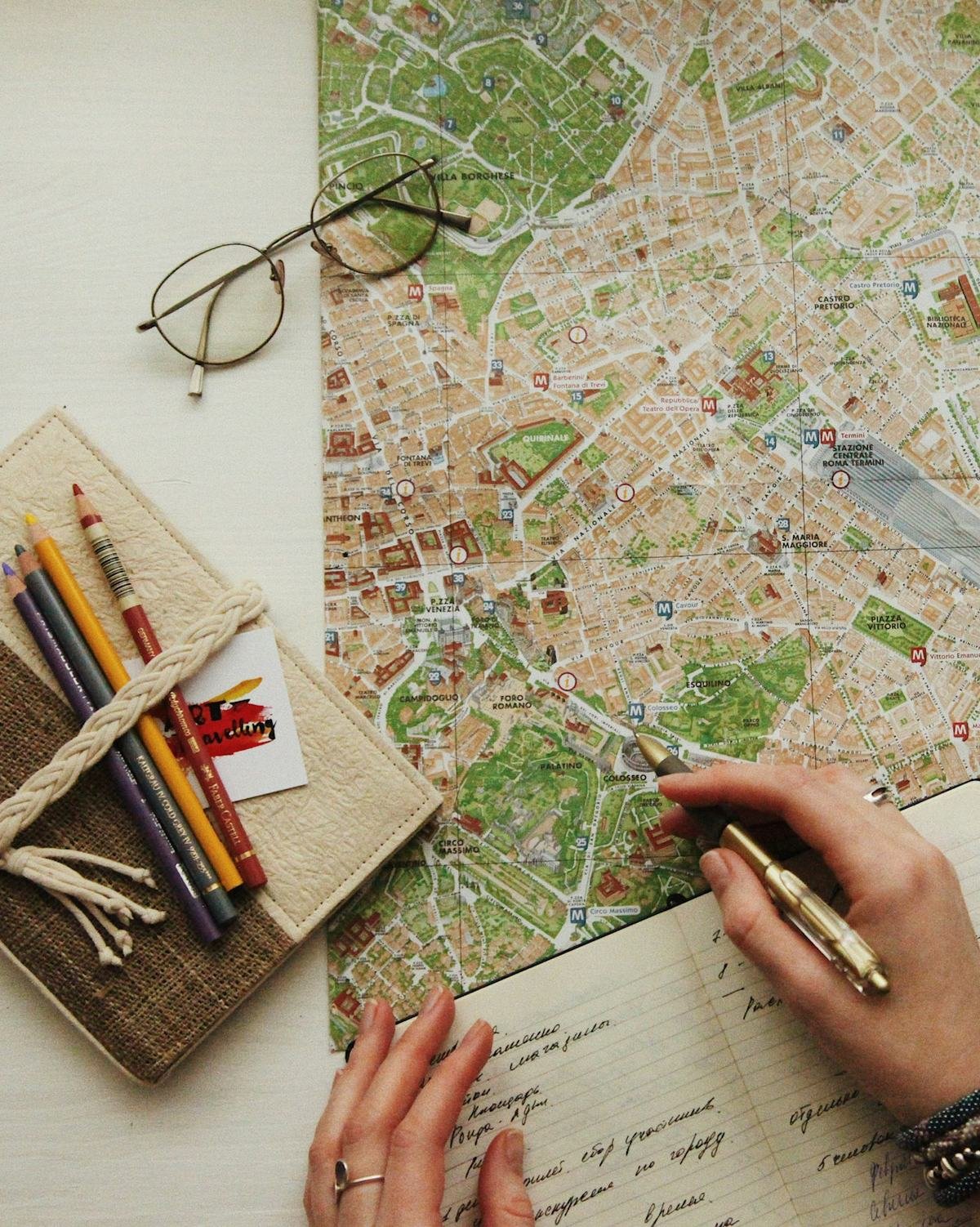 Hands writing travel notes beside a city map